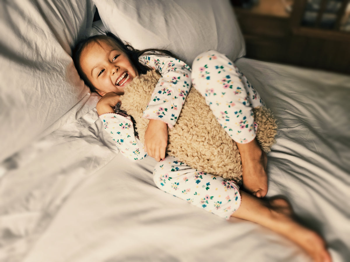 Child relaxing in bed with a Teddy hot water bottle.